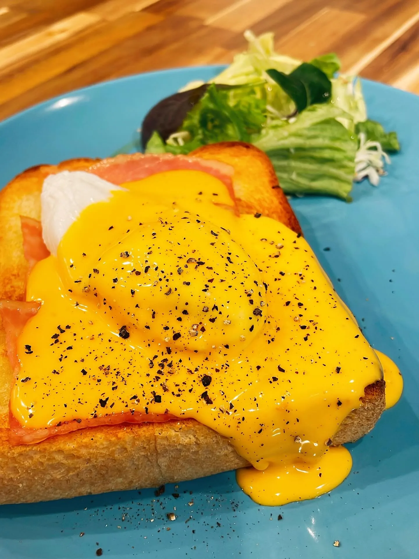 青い皿に盛られた、黄色い卵料理とサラダ